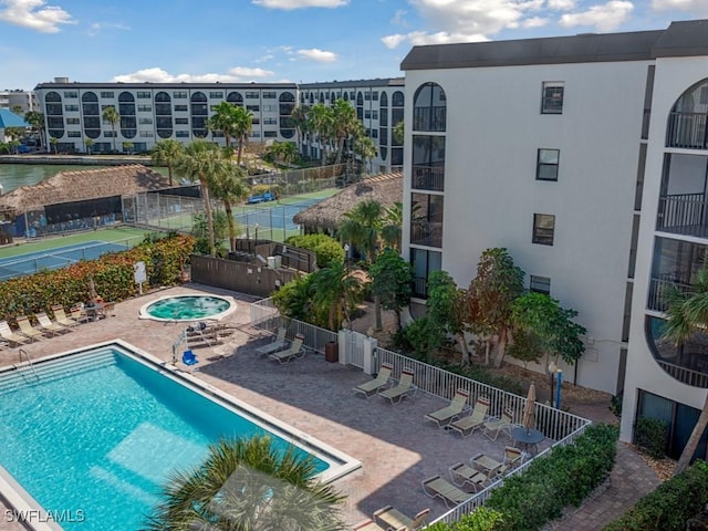 pool featuring a community hot tub, a patio area, and fence