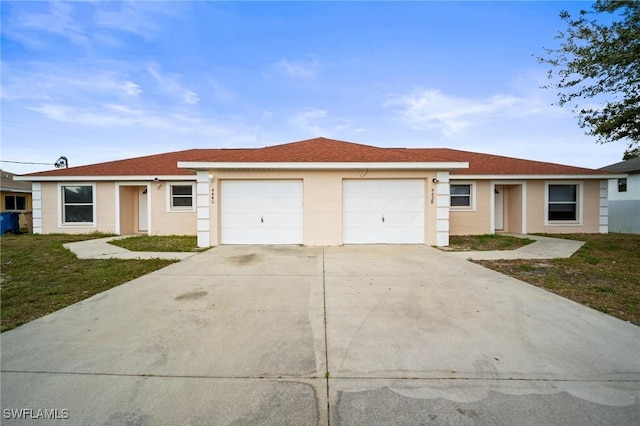 single story home featuring a garage, driveway, a front lawn, and stucco siding