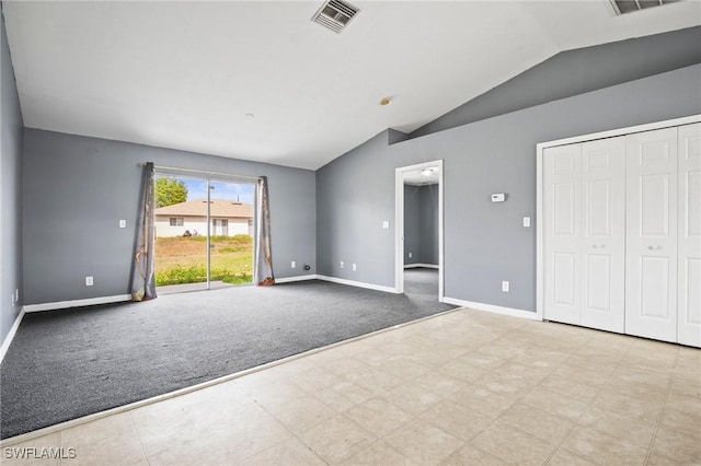 spare room featuring lofted ceiling, baseboards, light carpet, and visible vents