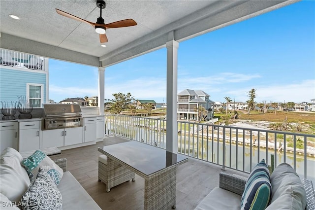 balcony featuring a ceiling fan, a residential view, a water view, a grill, and outdoor lounge area