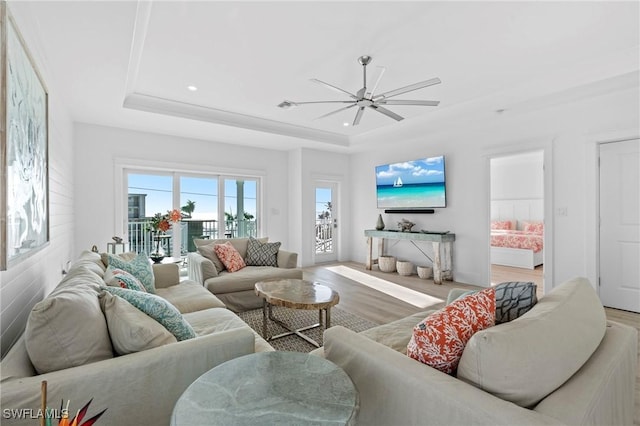 living area with baseboards, a ceiling fan, light wood-style flooring, a tray ceiling, and recessed lighting