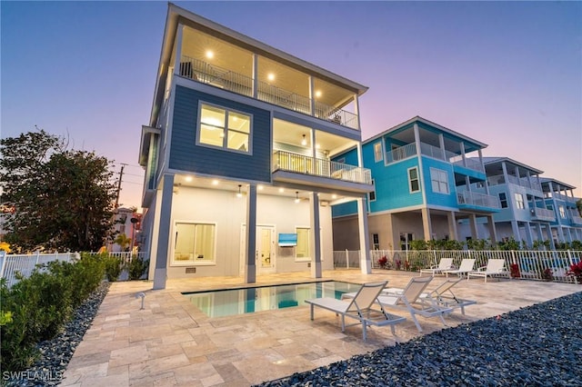 back of house at dusk with a patio, fence, and a fenced in pool