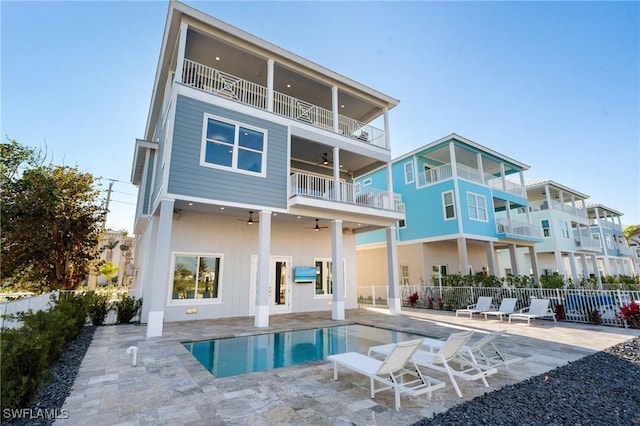 rear view of property featuring a fenced in pool, a ceiling fan, a balcony, a patio, and fence