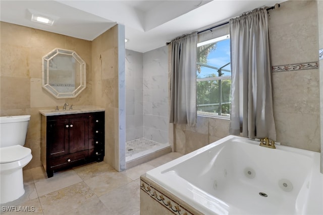 bathroom featuring toilet, a jetted tub, a tile shower, vanity, and tile walls