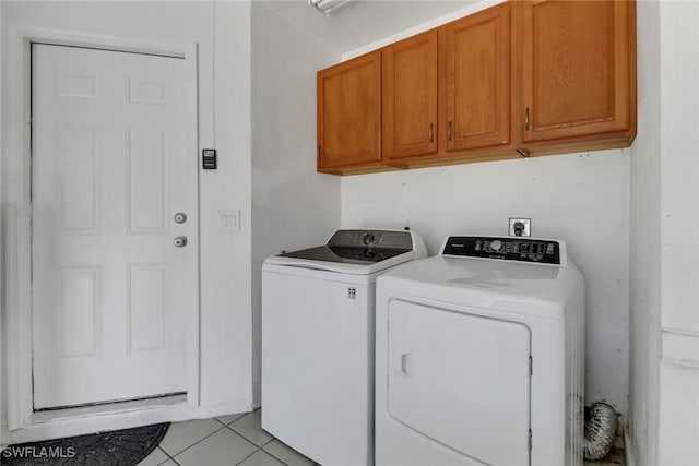 washroom with light tile patterned floors, washing machine and dryer, and cabinet space