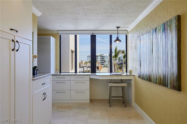 kitchen featuring a textured ceiling, a textured wall, white cabinetry, ornamental molding, and decorative light fixtures