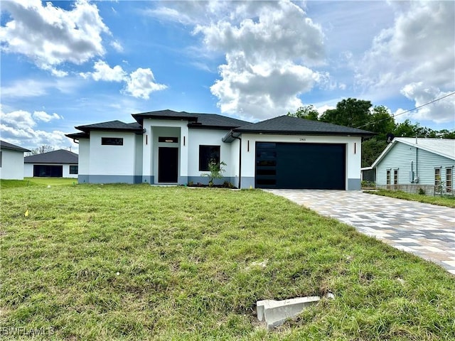 prairie-style house with a garage, a front lawn, decorative driveway, and stucco siding