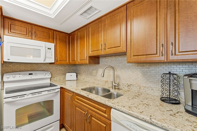 kitchen with white appliances, tasteful backsplash, visible vents, light stone countertops, and a sink