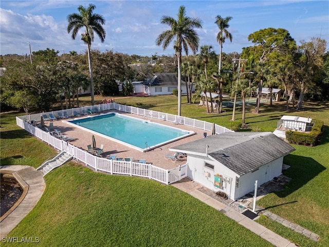 community pool with a lawn and a fenced backyard