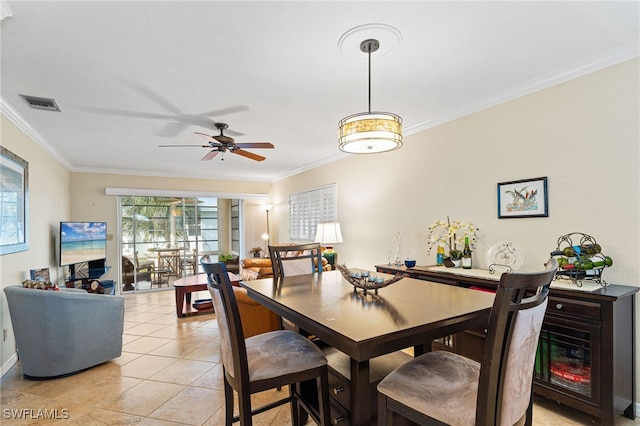 dining space featuring light tile patterned flooring, visible vents, a ceiling fan, and ornamental molding