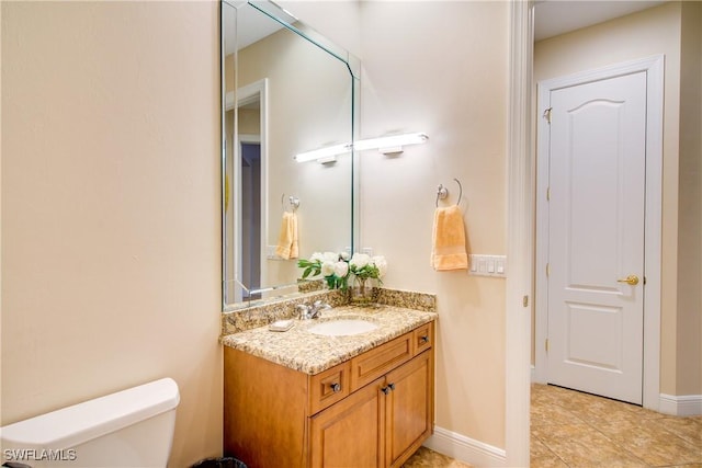 bathroom featuring baseboards, vanity, and toilet