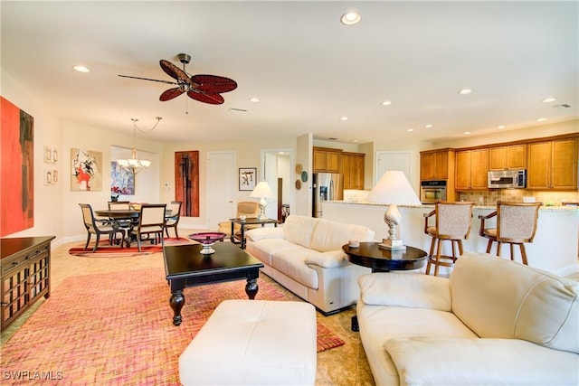 living room featuring baseboards, ceiling fan with notable chandelier, and recessed lighting