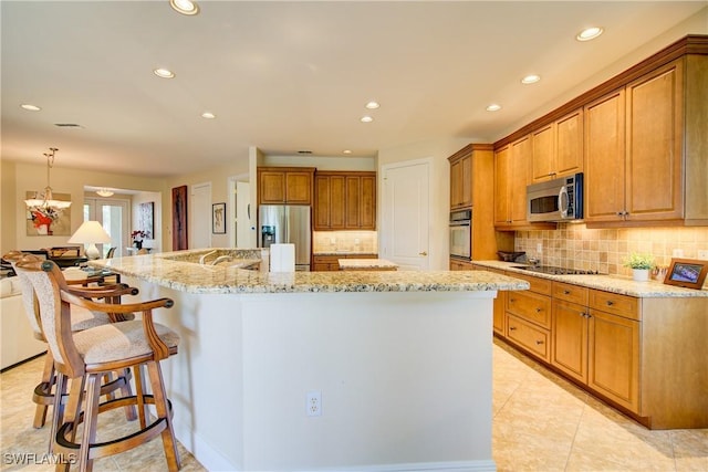 kitchen with stainless steel appliances, a spacious island, a kitchen bar, and light stone countertops