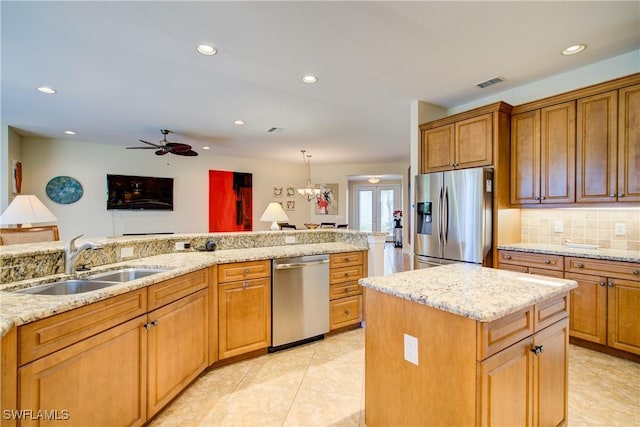 kitchen featuring visible vents, backsplash, appliances with stainless steel finishes, a sink, and light stone countertops