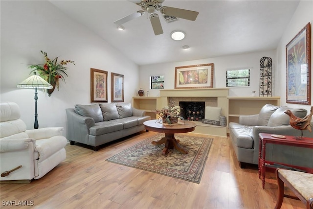 living room featuring lofted ceiling, ceiling fan, light wood-style flooring, a fireplace, and visible vents