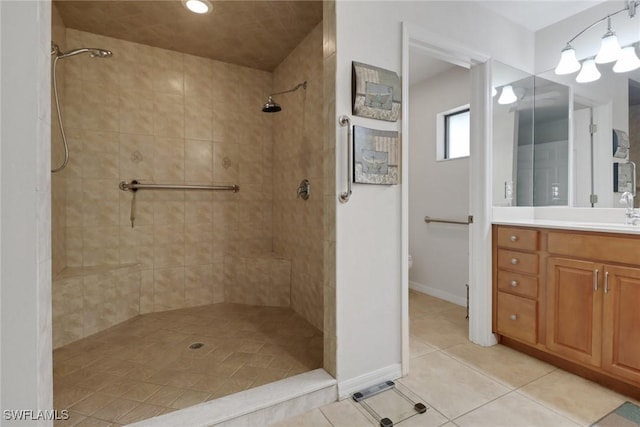 full bath with baseboards, tiled shower, vanity, and tile patterned floors