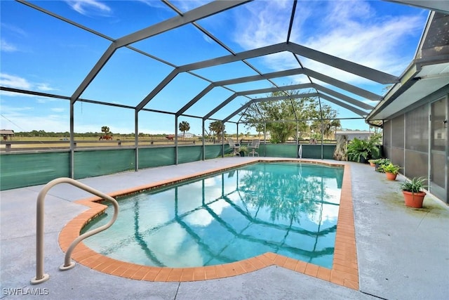 outdoor pool with a water view, glass enclosure, and a patio area