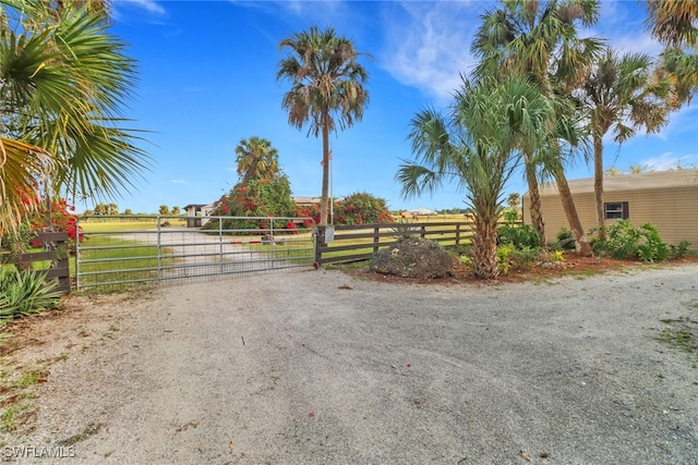 view of street featuring a gate, a rural view, a gated entry, and dirt driveway