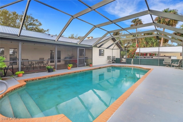 pool with glass enclosure, a patio, and a sunroom