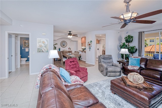 living room with ceiling fan, baseboards, and light tile patterned floors