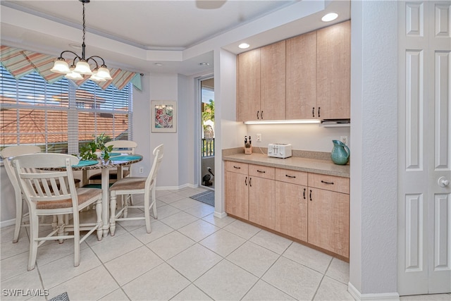 kitchen featuring light countertops, light brown cabinetry, a chandelier, pendant lighting, and light tile patterned flooring