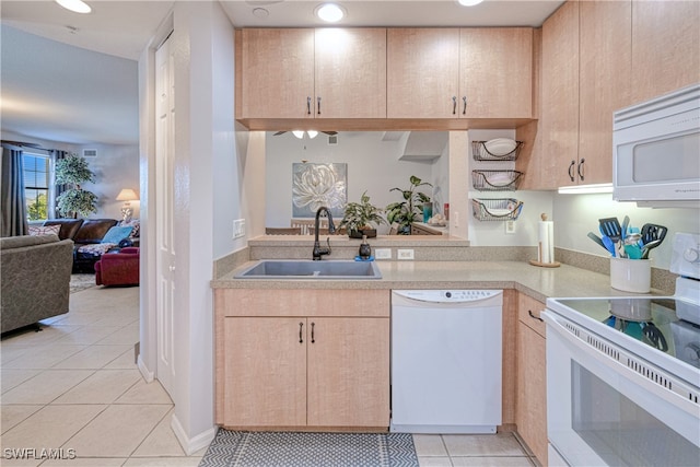 kitchen featuring white appliances, open floor plan, light countertops, light brown cabinetry, and a sink