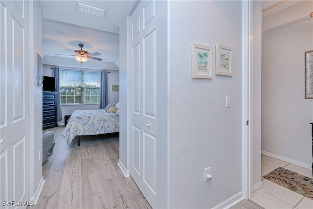 bedroom with a ceiling fan, visible vents, light wood-style flooring, and baseboards