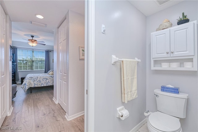 bathroom with toilet, wood finished floors, visible vents, a ceiling fan, and baseboards