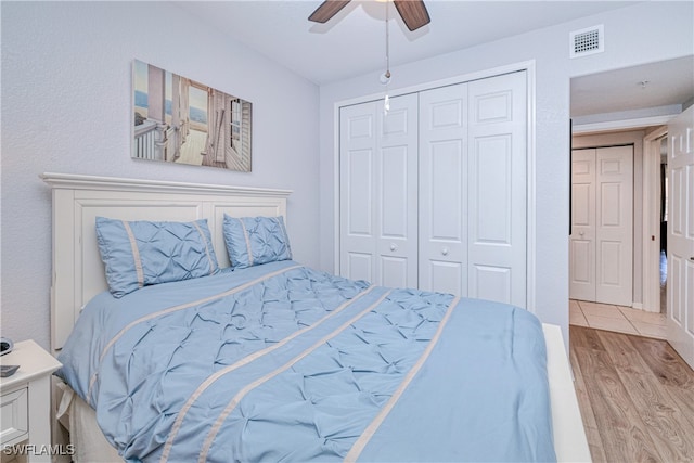 bedroom featuring light wood-style floors, a closet, visible vents, and a ceiling fan