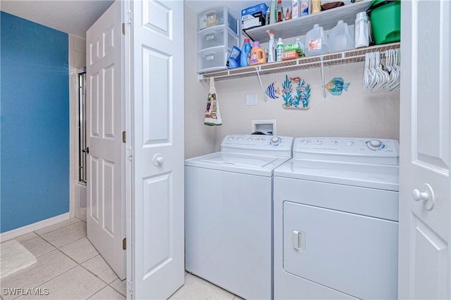 laundry room with laundry area, light tile patterned flooring, baseboards, and washing machine and clothes dryer