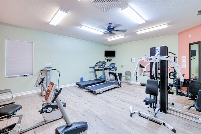 exercise room featuring a ceiling fan, a textured ceiling, visible vents, and wood finished floors