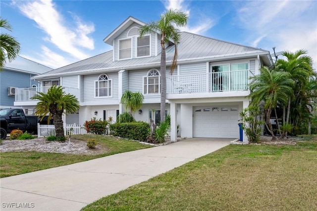 coastal inspired home featuring metal roof, an attached garage, a balcony, concrete driveway, and a front lawn