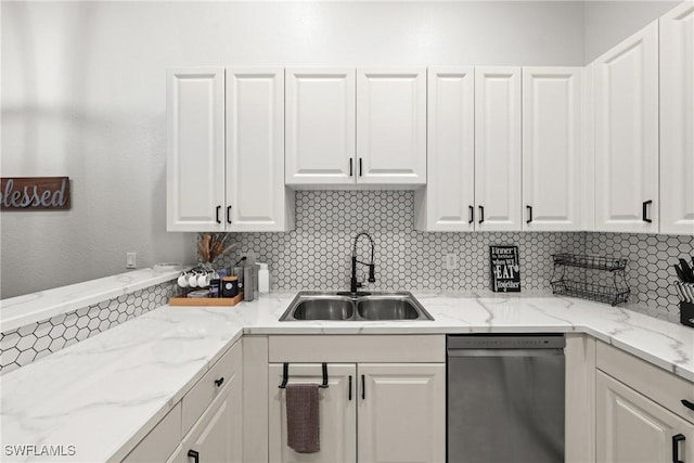 kitchen featuring tasteful backsplash, light stone countertops, stainless steel dishwasher, white cabinetry, and a sink