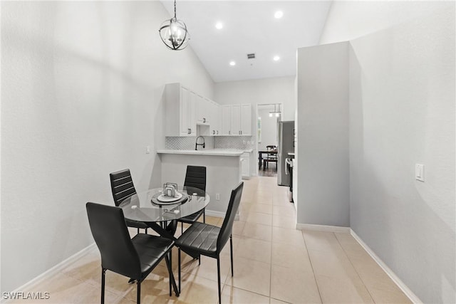 dining space featuring light tile patterned floors, a high ceiling, baseboards, and a chandelier