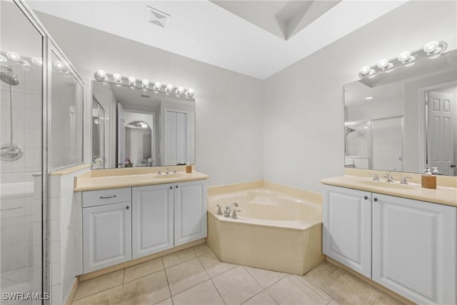 bathroom featuring a garden tub, two vanities, a stall shower, a sink, and tile patterned floors