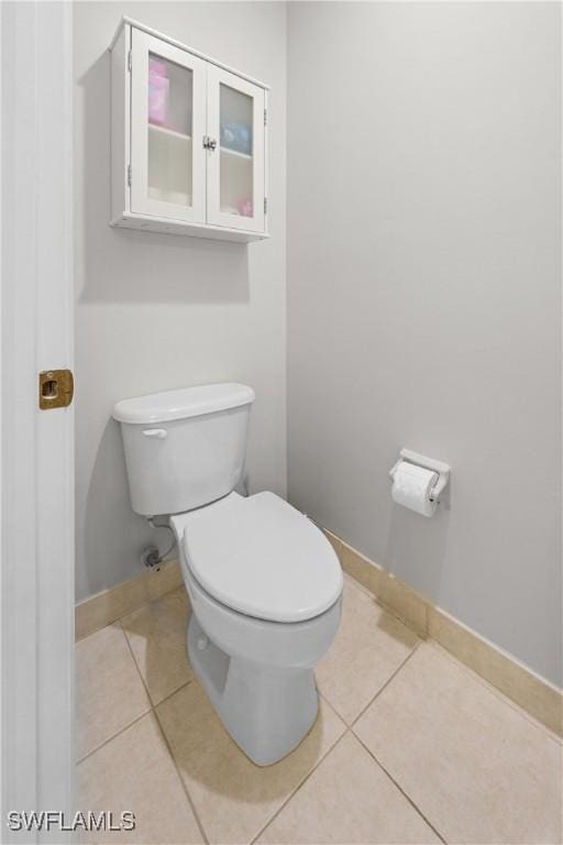 bathroom featuring tile patterned flooring, baseboards, and toilet