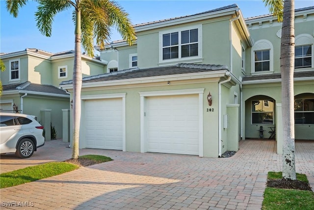 view of front facade with a garage, driveway, and stucco siding