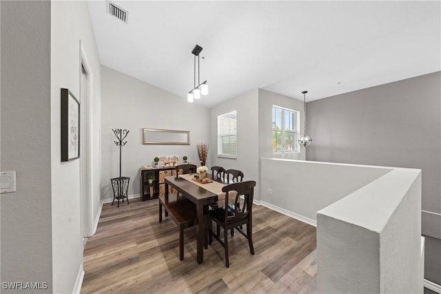 dining area with lofted ceiling, baseboards, visible vents, and wood finished floors