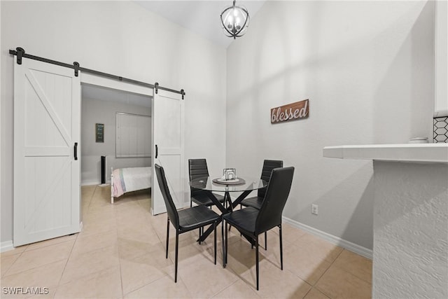 dining area with a barn door, light tile patterned flooring, a towering ceiling, and baseboards