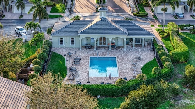 rear view of property featuring an outdoor pool, a tiled roof, fence, a patio area, and stucco siding