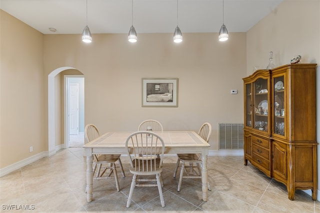 dining room featuring light tile patterned floors, baseboards, visible vents, and arched walkways