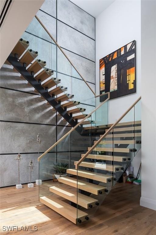 stairs with wood finished floors and a towering ceiling