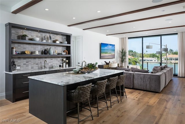 bar featuring beam ceiling, indoor wet bar, and light wood-style floors