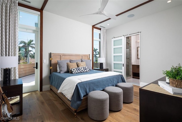 bedroom featuring recessed lighting, multiple windows, a barn door, and wood finished floors