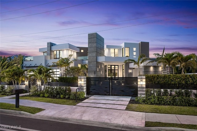 contemporary house featuring a fenced front yard, stucco siding, and a gate