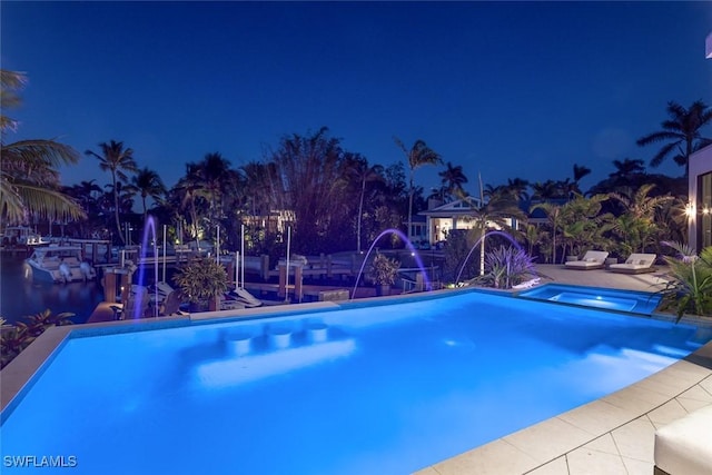 pool at twilight with a patio area and an infinity pool