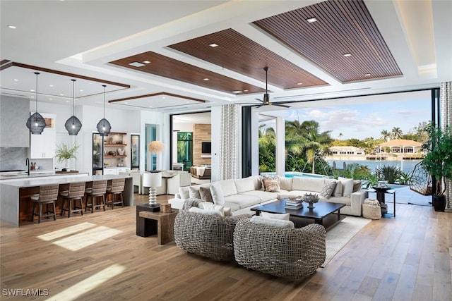 living area with floor to ceiling windows, a raised ceiling, a ceiling fan, and wood finished floors