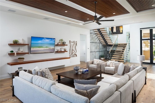 living room featuring baseboards, stairs, a tray ceiling, wooden ceiling, and wood finished floors