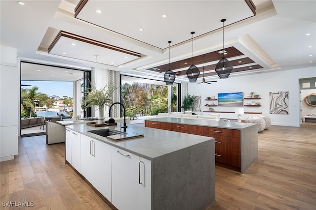 kitchen with open floor plan, a large island with sink, modern cabinets, and light wood-type flooring