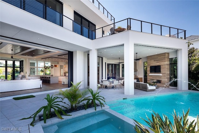 rear view of property featuring a pool with connected hot tub, ceiling fan, stucco siding, a balcony, and a patio